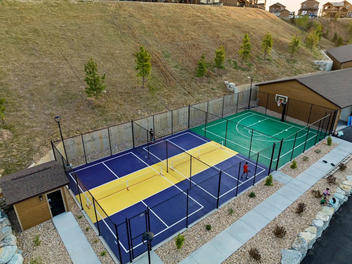 An active sports area featuring tennis and basketball courts, with players in motion and a scenic landscape surrounding the courts. The scene radiates energy, camaraderie, and opportunities for friendly competition.