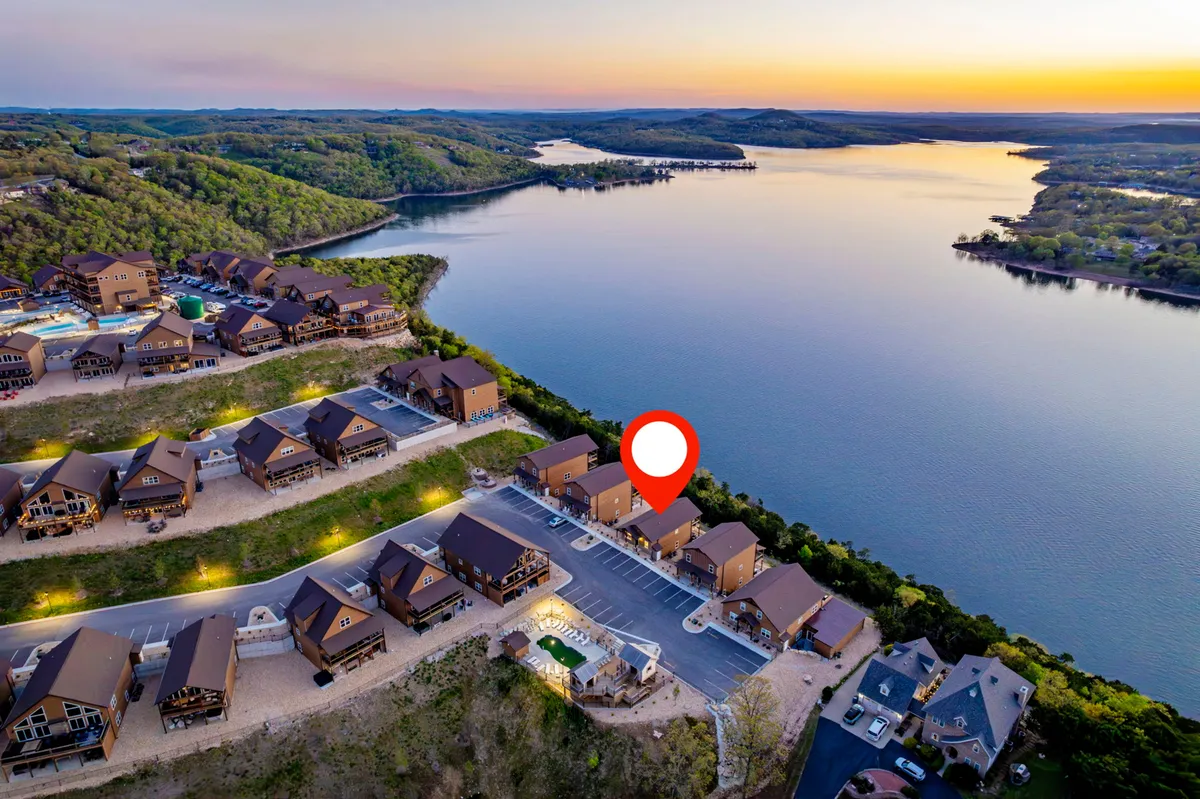 A sweeping exterior view captures Table Rock Lake nestled against a mountainous landscape, with residential cabins and a shimmering swimming pool in the foreground. The calm lake invites boating and fishing, while the pool and cabins suggest a vibrant lakeside community.