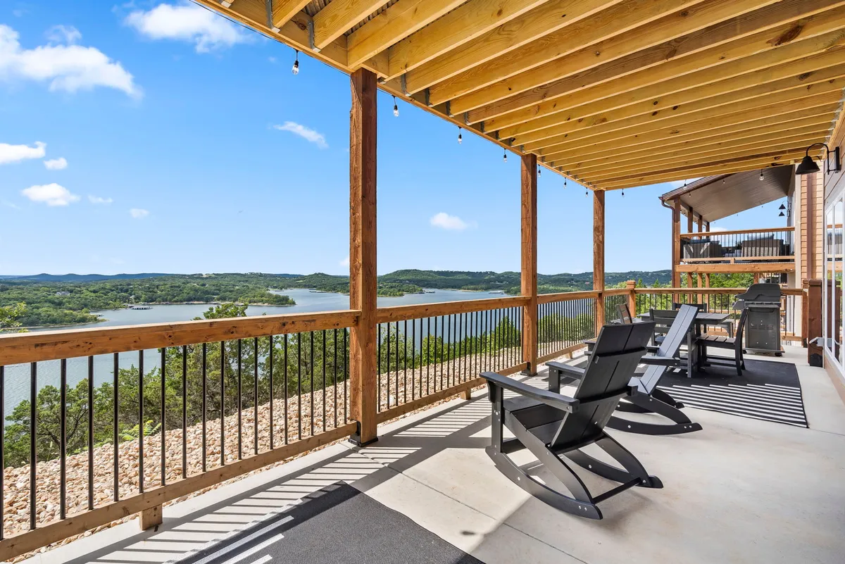 A wide wooden deck with classic Adirondack chairs overlooks a serene lake. The area is ideal for relaxing, social gatherings, or enjoying sunsets, offering a direct link between the indoor workspace and the outdoors.