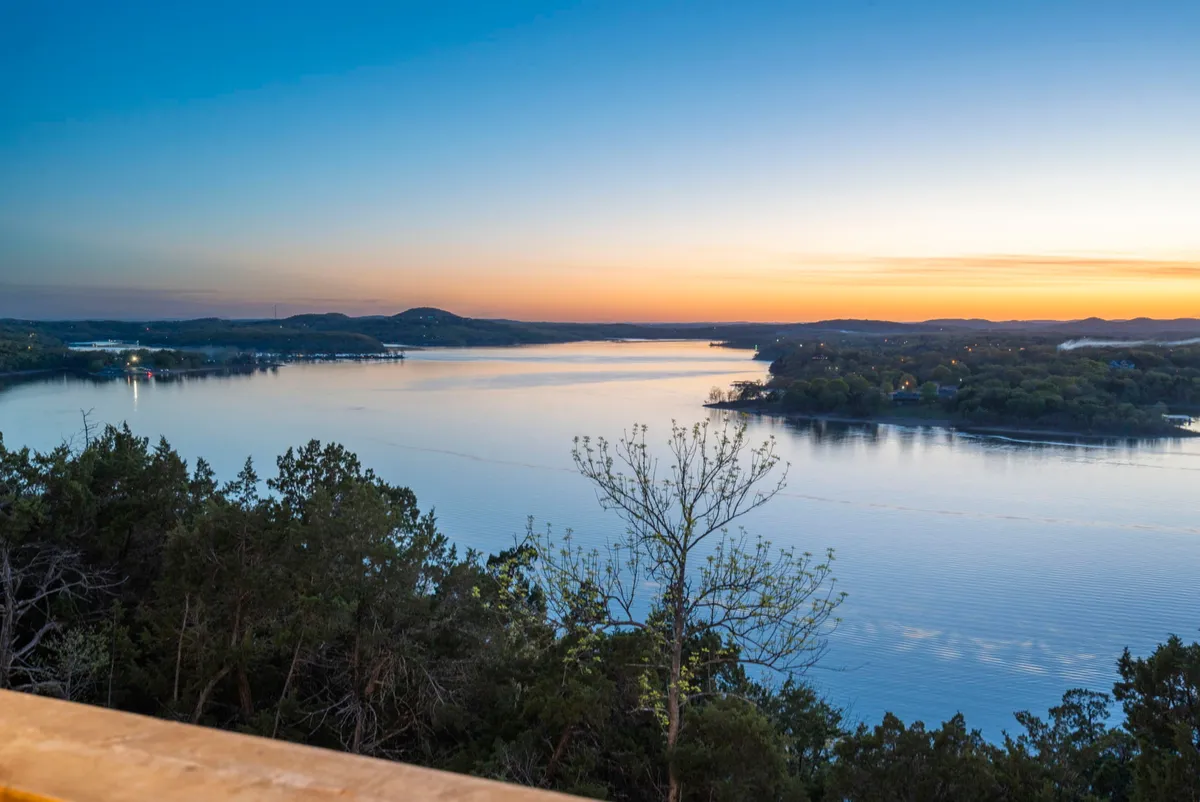 A breathtaking view of the lake at sunset, with golden hues reflecting off the water and tree silhouettes framing the horizon. The scene is peaceful, inviting moments of reflection or lakeside picnics as described in the text.